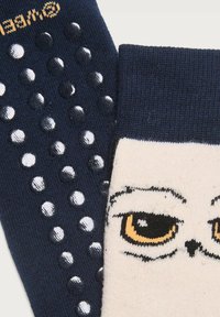 Calze con un corpo blu marino caratterizzato da puntini antiscivolo in gomma e una sezione color crema con una faccia di gufo in stile cartone animato e occhi dettagliati.
