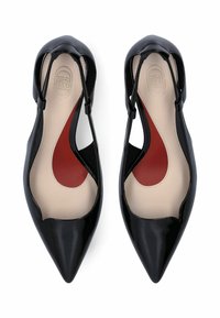 Paire de ballerines à bout pointu en cuir verni noir avec brides arrière, semelles intérieures beige et rouge, vues de dessus sur fond blanc.