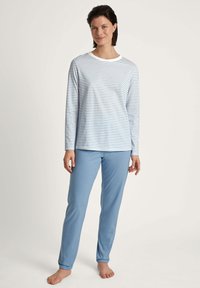Langärmliges, weiß-blau gestreiftes Oberteil mit Rundhalsausschnitt, kombiniert mit hellblauen, unifarbenen, geraden Hosen aus weichem Stoff.