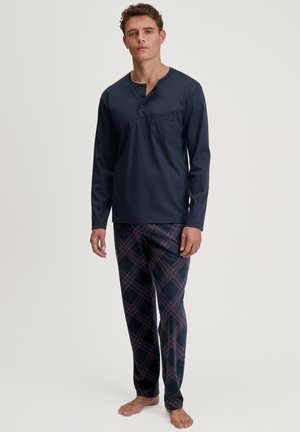 Marineblaues Langarmoberteil mit Henley-Ausschnitt und Tasche; karierte Schlafanzughosen in Marineblau, Rot und Weiß; weicher, leichter Stoff.