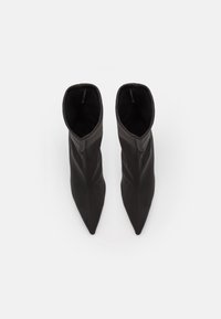 Černé kožené kotníkové boty se špičatou špičkou, s přiléhajícím článkem a hladkým povrchem. Minimalistický design bez viditelného kování.