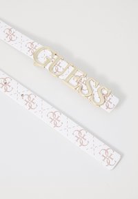 Ceinture blanche à motifs avec un logo doré "GUESS". Présente une surface texturée et de subtils accents roses, mettant en avant un design moderne.
