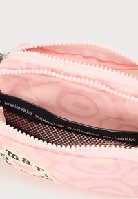 Ροζ υφασμάτινη θήκη με δύο διαμερίσματα με φερμουάρ, μαύρη πόρπη από δίχτυ και λογότυπο Marimekko στο εσωτερικό φόδρα και στο εμπρόσθιο σημείο.