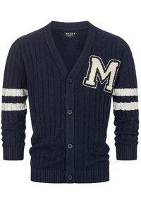 Mørkeblå kabelstrikket cardigan med V-hals, udstyret med en hvid "M" applikation og stribede hvide detaljer på ærmerne. Fem sorte knapper.