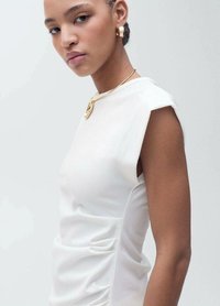 Top alb fără mâneci, cu un design ajustat, având o textură discretă, cu nervuri, și un detaliu cu mânecă asimetric, completat cu un colier cu pandantiv din aur.