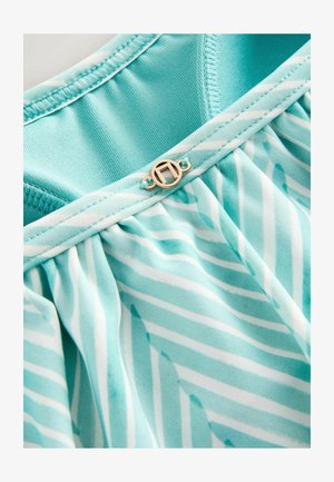 Et lyseblåt stof med hvide skråstriber, med en samlet design og en hardware accent i guldtoner ved halsudskæringen.