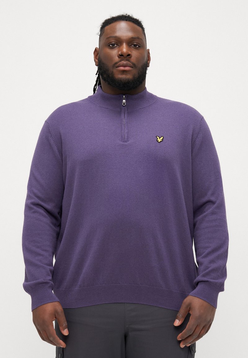 Purple knit pullover with a zip neckline and ribbed cuffs. Features a small yellow logo on the chest. Soft texture with a relaxed fit.