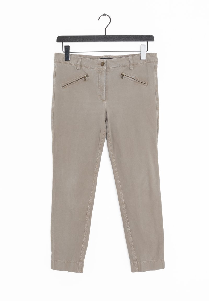 Pantalon beige slim-fit avec poches zippées à l'avant suspendu sur un cintre noir sur fond blanc.