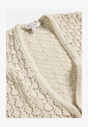 Cremefarbener, offen gestrickter Cardigan mit gewelltem Rand, der ein filigranes florales Spitzenmuster aufweist, mit einem Größenetikett 38/40 von Cellbes aus Schweden.