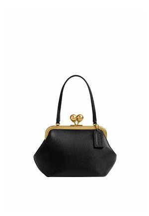Sac à main en cuir noir avec une poignée courte, un cadre métallique doré, une fermeture à clapet et une petite étiquette de marque suspendue sur le côté.