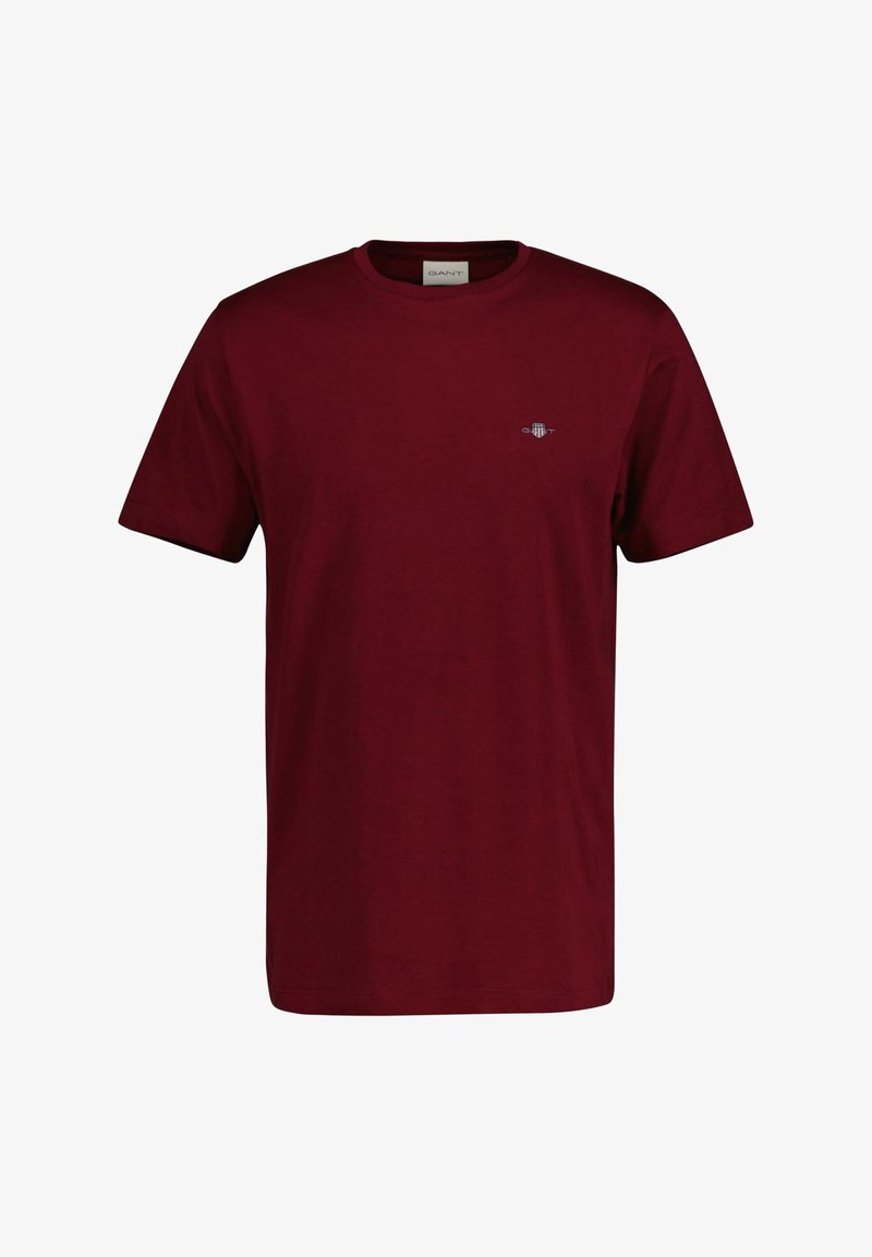 T-shirt uni bordeaux à manches courtes avec col rond, petit logo poitrine côté gauche et étiquette à l'intérieur du col.