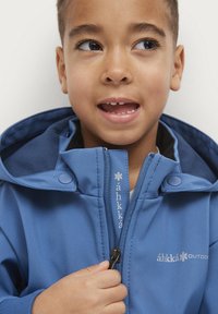 Blaues Outdoor-Jacke mit Kapuze, ausgestattet mit einem durchgehenden Reißverschluss, Druckknöpfen und Logodetails. Der Stoff wirkt glatt und leicht.