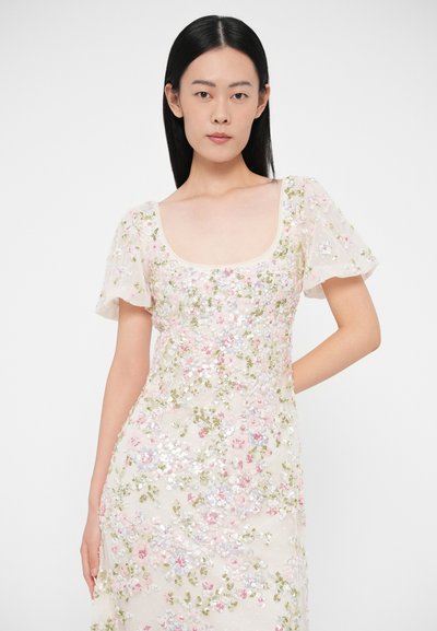 Zdobené šaty z priehľadnej látky, s hranatým výstrihom a krátkymi nafúknutými rukávmi. Ozdobené pastelovými kvetinovými flitrami a zelenými akcentmi.