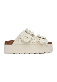 Sandalias de plataforma en lona color crema con bordes deshilachados, correas con doble hebilla, tachuelas decorativas y una entresuela con textura de corcho. Suela ligera y gruesa.