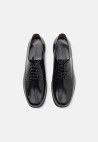 Chaussures de ville en cuir noir avec une finition lisse, enfilage à lacets, bout arrondi et intérieur subtilement marqué.