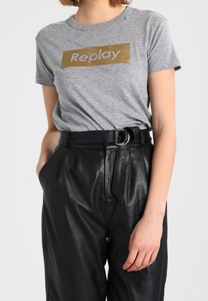 Szary t-shirt z złotym logo "Replay", w połączeniu z czarnymi skórzanymi spodniami o wysokim stanie, z paskiem z okrągłą metalową klamrą.
