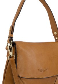 Tan leather handbag with a smooth texture, featuring a structured design, adjustable shoulder strap, and gold hardware accents.
