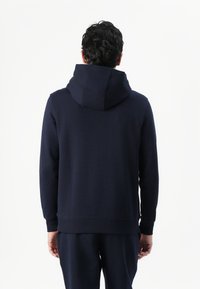 Sweat à capuche bleu marine, en tissu mélange de coton, coupe décontractée, poignets et ourlet côtelés, couture plate au niveau de la capuche, design minimaliste.