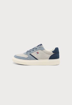Baskets basses avec des empiècements en daim gris, bleu clair et bleu marine, semelle blanche, lacets et petit logo rouge, blanc et bleu sur le côté.