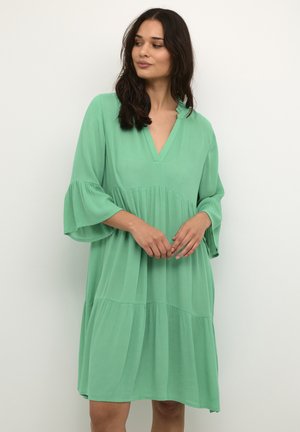 Green, knee-length dress with a V-neck and three-quarter bell sleeves. Made of lightweight fabric with a tiered design and subtle texture.