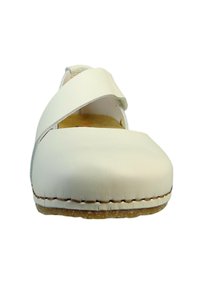 Chaussure en cuir blanc avec un design à brides croisées, bout arrondi et semelle en caoutchouc beige. Présente des coutures visibles le long du bord.