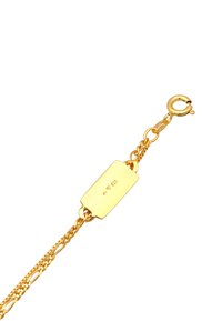 Bracciale color oro caratterizzato da una catena allungata e un'etichetta rettangolare. L'etichetta è incisa con un marchio e attaccata tramite un gancetto.