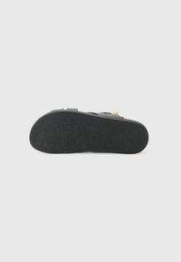 Black rubber sandal sole with textured surface, slight heel, and minimalistic design. Features no additional patterns or accents.