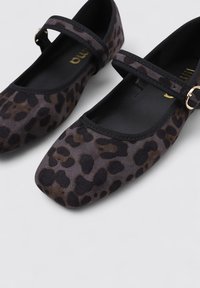 Bailarinas de estampado de leopardo, hechas de tela suave, con punta cuadrada y una correa negra con un acento de hebilla dorada. Forro interior negro.