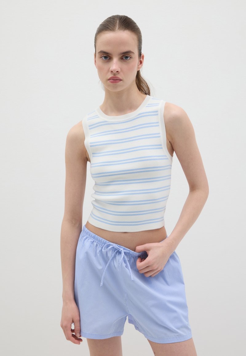Gestreiftes Tanktop in Weiß und Hellblau mit figurbetontem Schnitt. Kombiniert mit hellblauen, gestreiften Shorts mit Kordelzug. Glatte Textur.