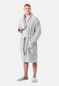 Pilkos plush vonios chalatą su šaliu apykakle, juosmens juosta ir dviem priekinėmis kišenėmis. Suderinta su atitinkamais šlepetėmis; matoma minkšta tekstūra.
