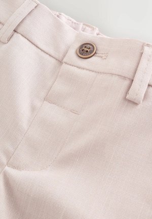 Ljusrosa byxor med en texturerad tygkvalitet, utrustade med en brun knapp och en bakficka. Detaljer inkluderar skräddarsydda sömmar och bältesöglor.