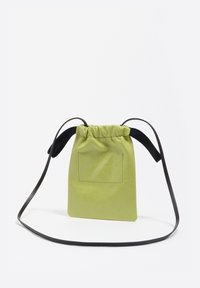 Bolso de cuero verde con cordón y correa negra, de forma rectangular, textura lisa y detalle de bolsillo trasero.