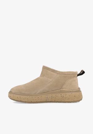 Stivali alla caviglia in suede beige con punta tonda, lati elasticizzati e suola in gomma beige maculata. Include un pratico lembo sul retro per facilitare l'indossamento.