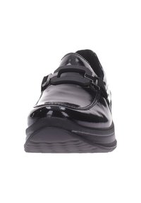 Mocasín negro brillante con hebilla decorativa en la parte superior y suela texturizada, fotografiado de frente sobre un fondo blanco.