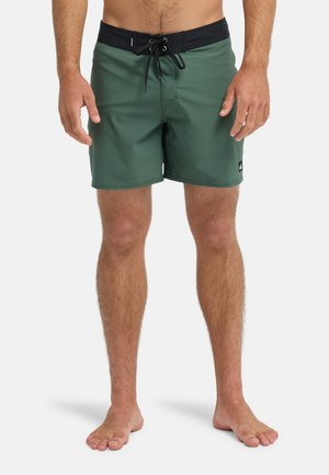 Grüne Badeshorts aus schnell trocknendem Material, mit einem schwarzen Kordelzug am Bund, glatter Textur und einem kleinen Markenlogo am Saum.