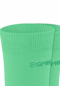 Para jasnych zielonych skarpetek sportowych z dzianiny z subtelnym logo marki częściowo widocznym na mankiecie.