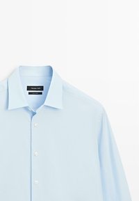 Lyseblå skjorte med knaplukning lavet af bomuld. Har en klassisk krave, lange ærmer og hvide knapper foran. Mærke: Massimo Dutti.