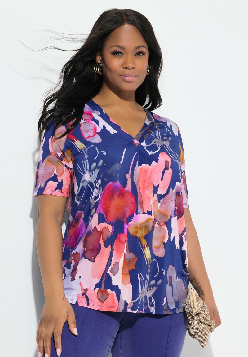 Top floreale con scollatura a V di colore navy, caratterizzato da motivi in stile acquerello nei colori rosa, arancione e giallo. Maniche corte con vestibilità ampia.