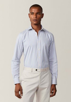 Camisa de manga larga a rayas azul claro y blanca con cuello tipo button-down; tela suave; corte ajustado con un diseño limpio y detalle en los puños.