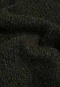 Tejido de punto verde oscuro con una superficie texturizada y suave, que presenta una mezcla de puntos apretados y sueltos, creando un aspecto estratificado.