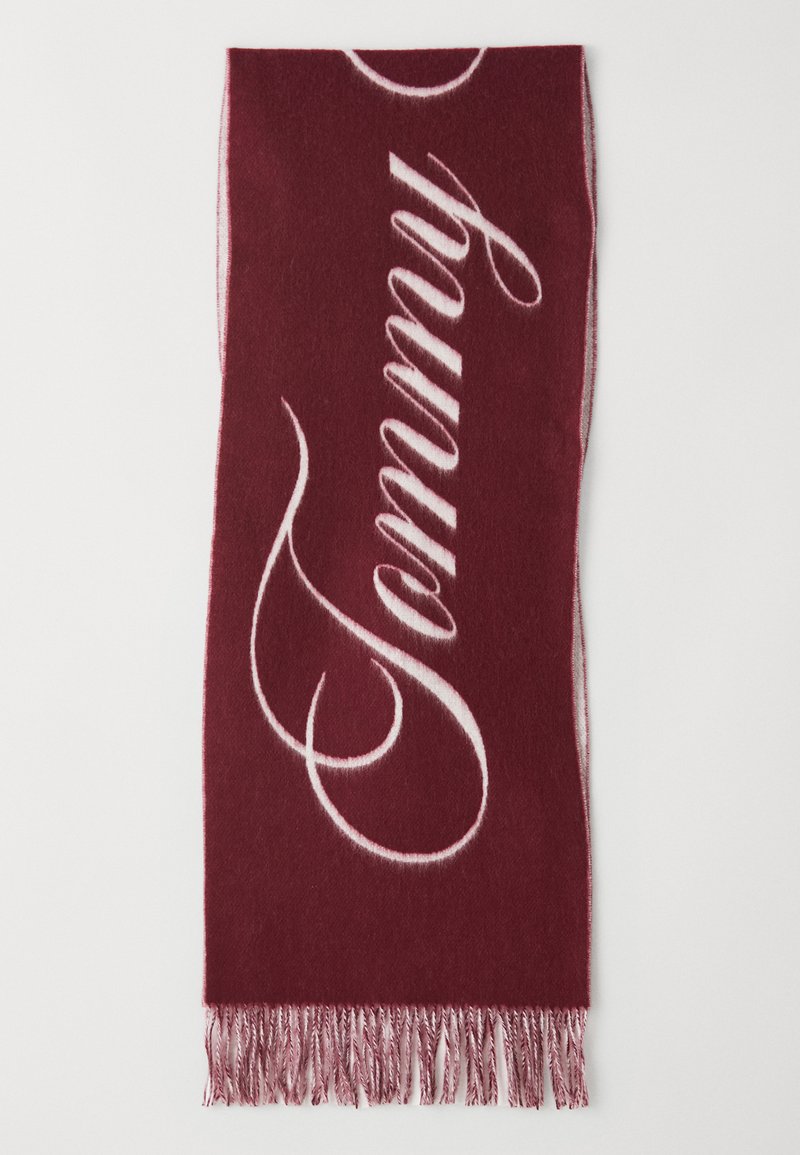 Burgundy scarf with white "Tommy" text in cursive. Features soft texture and fringed ends, designed for warmth and style.