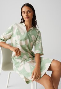 Green floral dress with oversized short sleeves, featuring white and light green flower patterns. The fabric appears smooth and lightweight.
