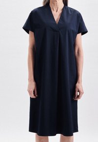 Marinblå klänning i ett tyg med mjuk finish, med V-ringning, korta ärmar och en avslappnad, knälång silhuett.