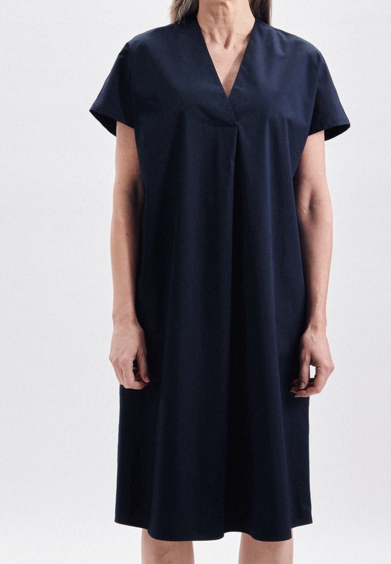 Marinblå klänning i ett tyg med mjuk finish, med V-ringning, korta ärmar och en avslappnad, knälång silhuett.