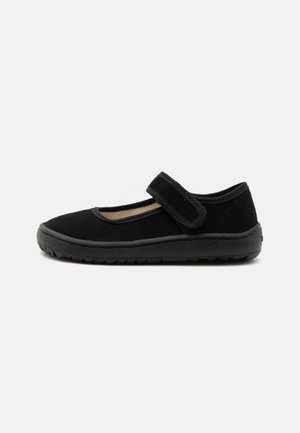 Chaussure Mary Jane noire en tissu texturé, bride Velcro réglable, semelle en caoutchouc et profil bas, vue de côté sur fond blanc.