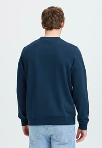 Sudadera azul marino, de mangas largas, con cuello redondo, fabricada en un tejido suave, con una textura sutil, ajustada en los puños y el dobladillo, la vista trasera no presenta adornos.