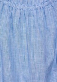 Jasnoniebieska tkanina z drobnymi pionowymi paskami, z marszczonym elastycznym paskiem w talii. Miękka tekstura i lekki materiał.