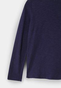 Modrá bavlněná košile s dlouhým rukávem a jemnou melírovanou strukturou, zobrazená z boku na bílém pozadí.