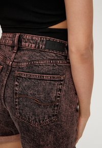 Jeansowe szorty w kolorze czarnym z wyblakłym różowym praniem, z kontrastowymi szwami, dwiema tylnymi kieszeniami oraz skórzaną metką na pasku.