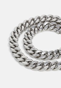 Thick silver Cuban link chain necklace with large interlocking oval links on a white background.